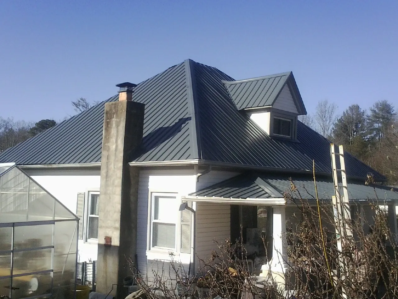 Dark blue standing seam metal roof on a white farmhouse with dormer — Slate & Tile Roof Repair by Roofing Brothers in Macungie