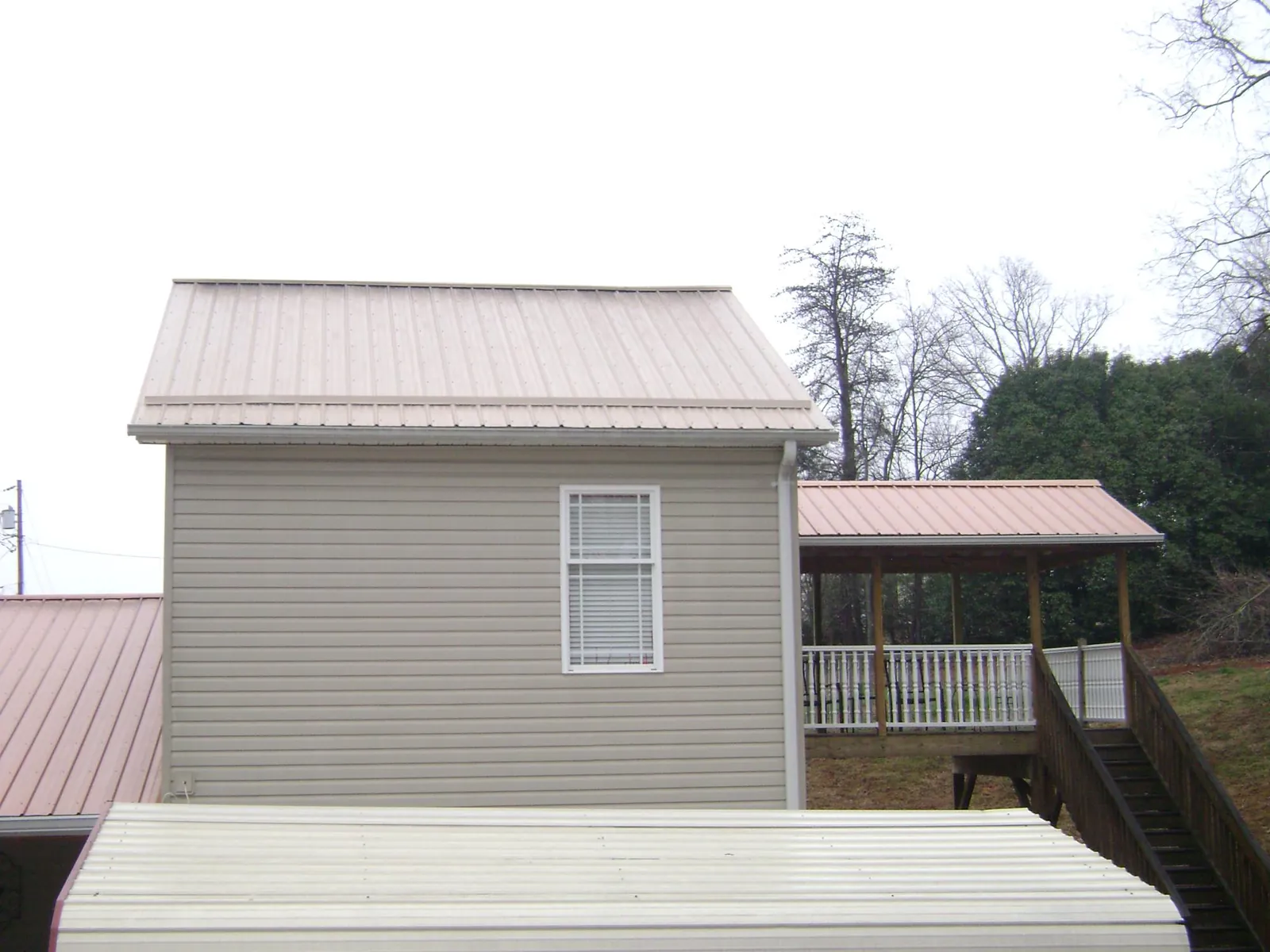 Tan metal roofs on a two story addition and attached porch, from a Roof Replacement job in Macungie