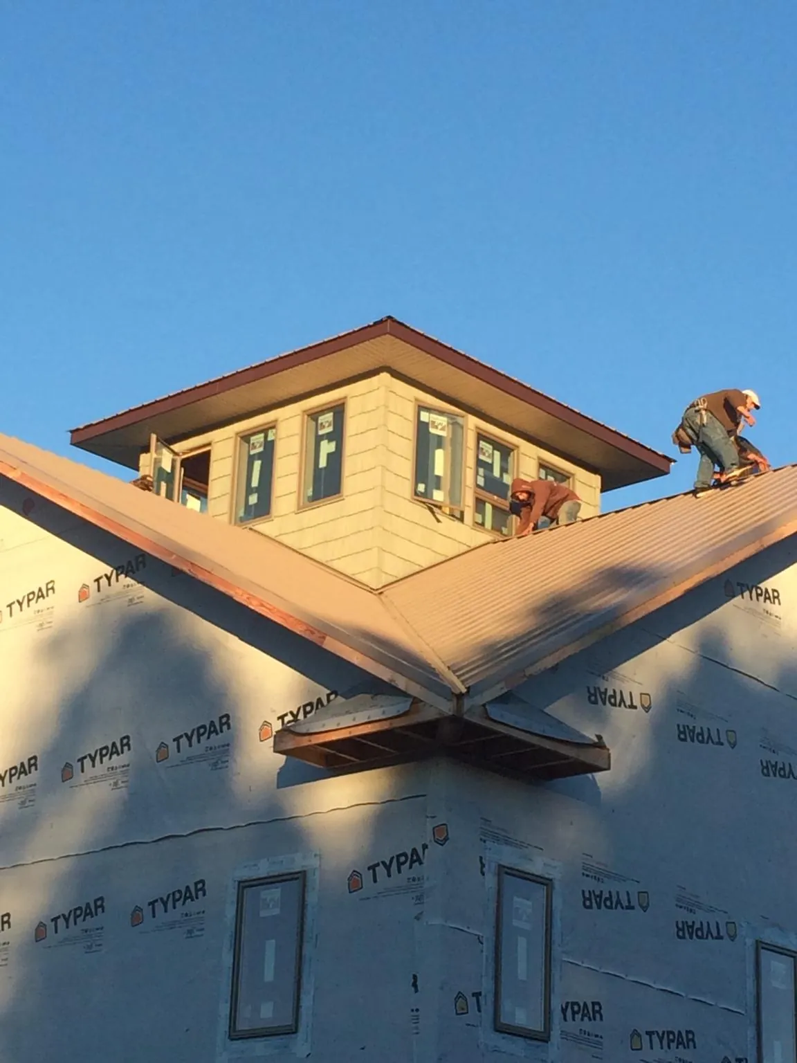 Roofers working around a rooftop cupola on a new metal roof at sunset — Roof Waterproofing in Macungie by Roofing Brothers
